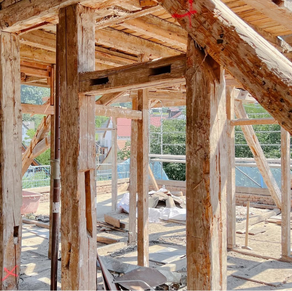 Dachstuhl und Holzrahmenkonstruktion eines Gebäudes während der Sanierung bei Tageslicht.