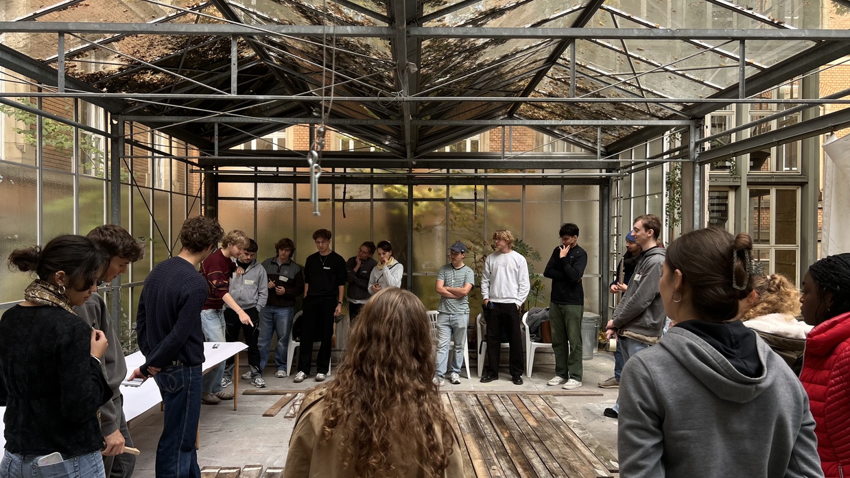 Gruppe junger Menschen steht im Kreis in einem Gewächshaus.